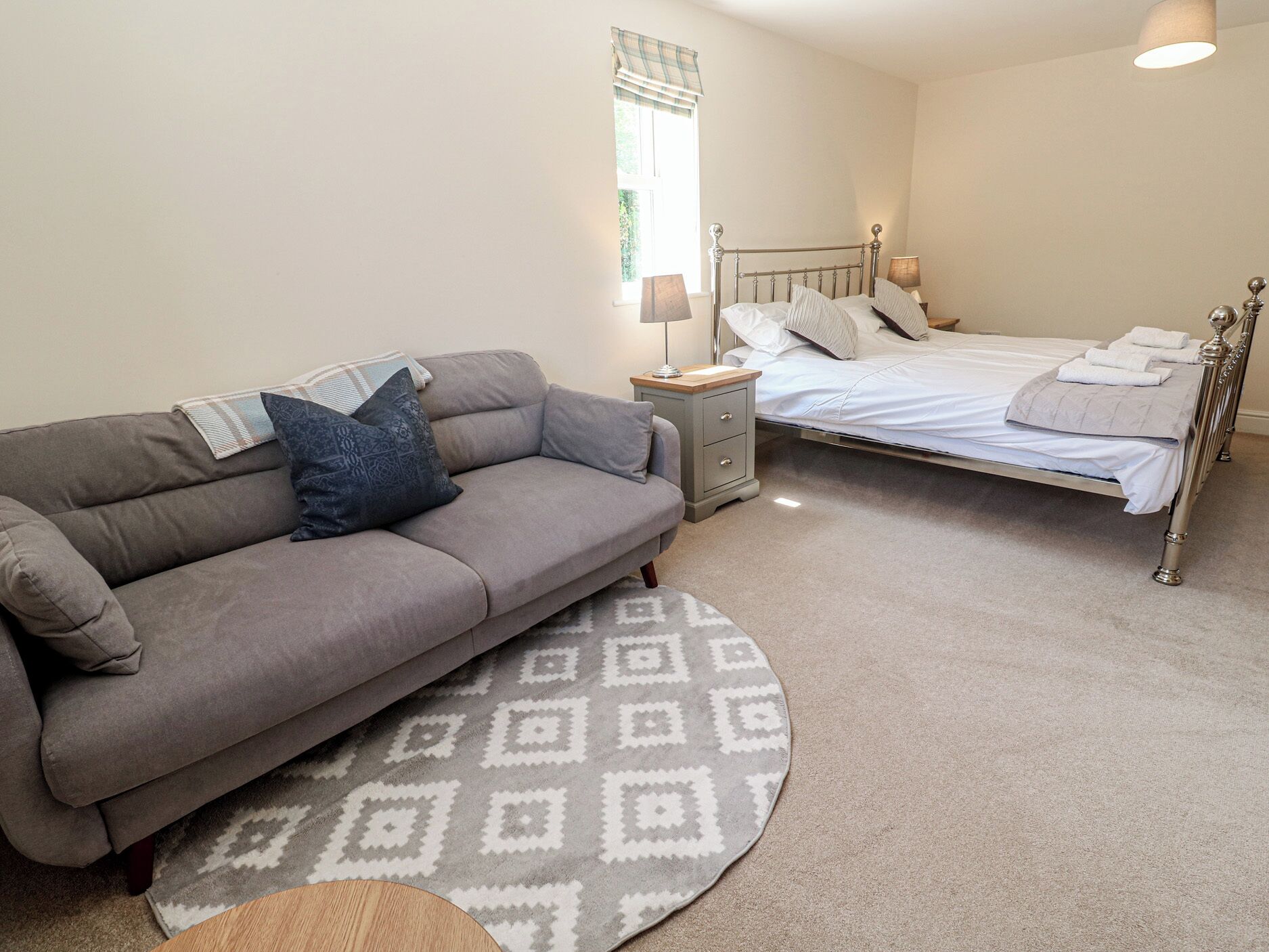 Ein Schlafzimmer mit Bett, Sofa, Nachttisch und Lampe.