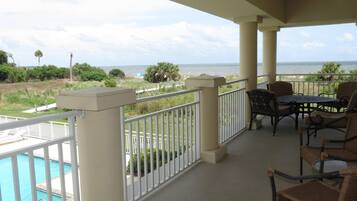 Enjoy ocean views from this balcony, featuring a pool and lush surroundings.