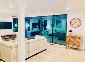 A modern living room with a sofa, a wooden cabinet, and a large clock on the wall. - Treehouse Living near St. Davids Hospital/UT/Capitol (Austin)