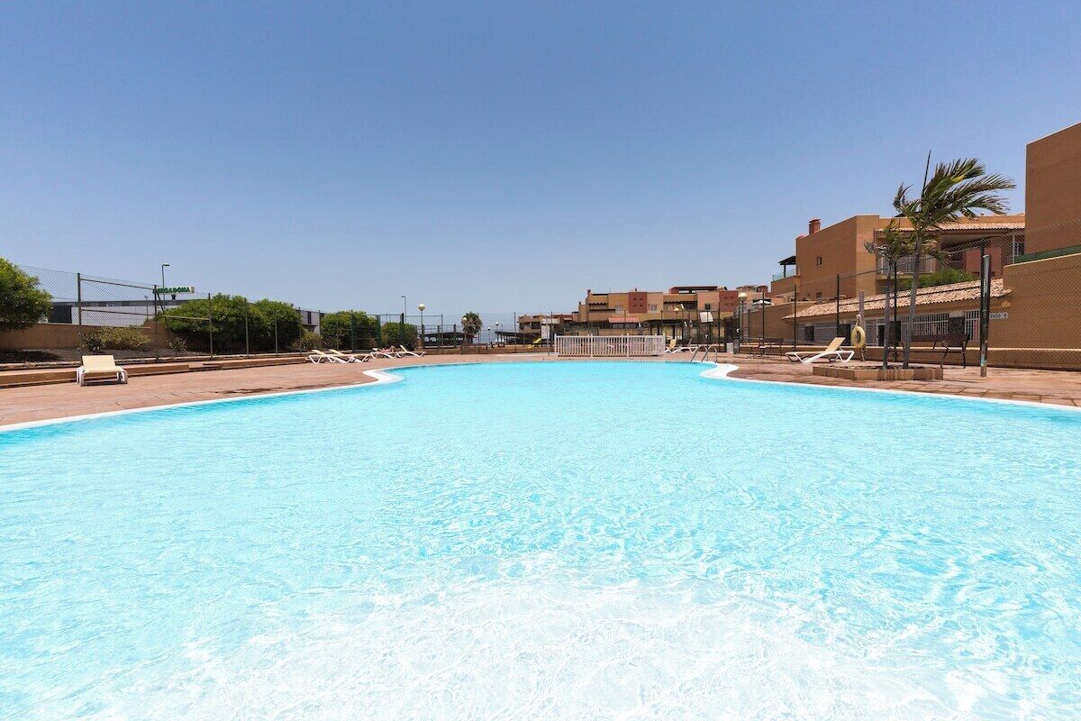 Uma grande piscina com espreguiçadeiras e céu claro.
