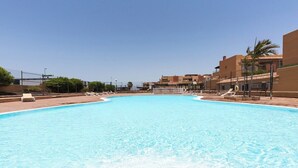 Una gran piscina con sillas de descanso y un cielo despejado.