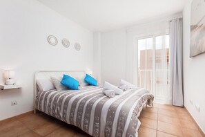Et soveværelse med en seng, puder, et natbord med lampe, et vindue med gardiner og en væg med tre runde dekorationer.
