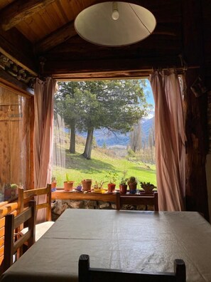 Una cabaña rústica de madera con un ventanal grande, una mesa y sillas.