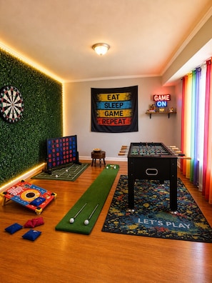 Quarto com dardos, mesa de pebolim e tapete para dardos.