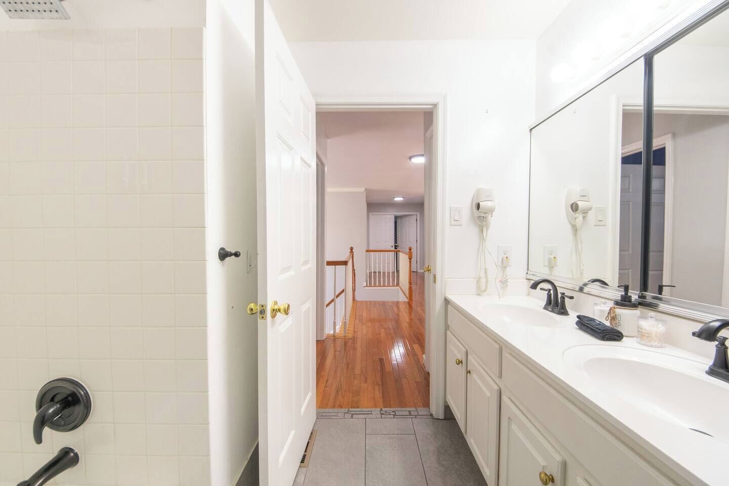 A bathroom with a white sink, a large mirror, and a shower area.