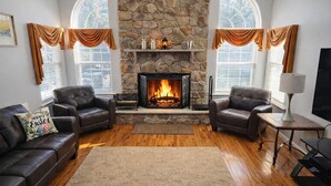 A living room with a stone fireplace, leather sofas, and a rug.