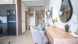 A modern kitchen with a built-in refrigerator, a dining area with a wooden table and chairs, and a hallway leading to a bedroom. - Oleas Suite Earth & Private Pool (Heraklion)