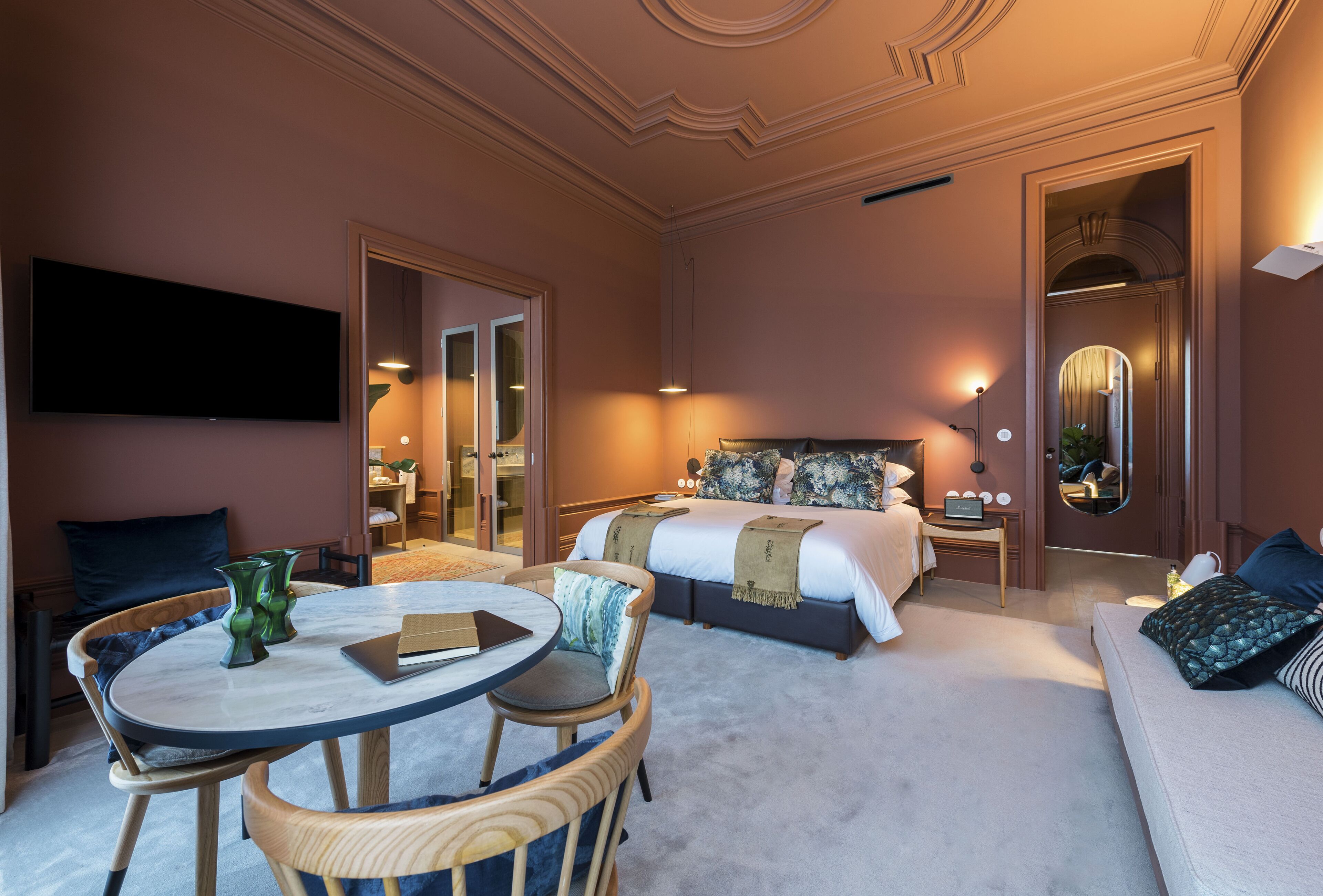 Une chambre d’hôtel équipée d’un lit, d’une table de chevet, d’une lampe et d’un téléviseur fixé au mur.