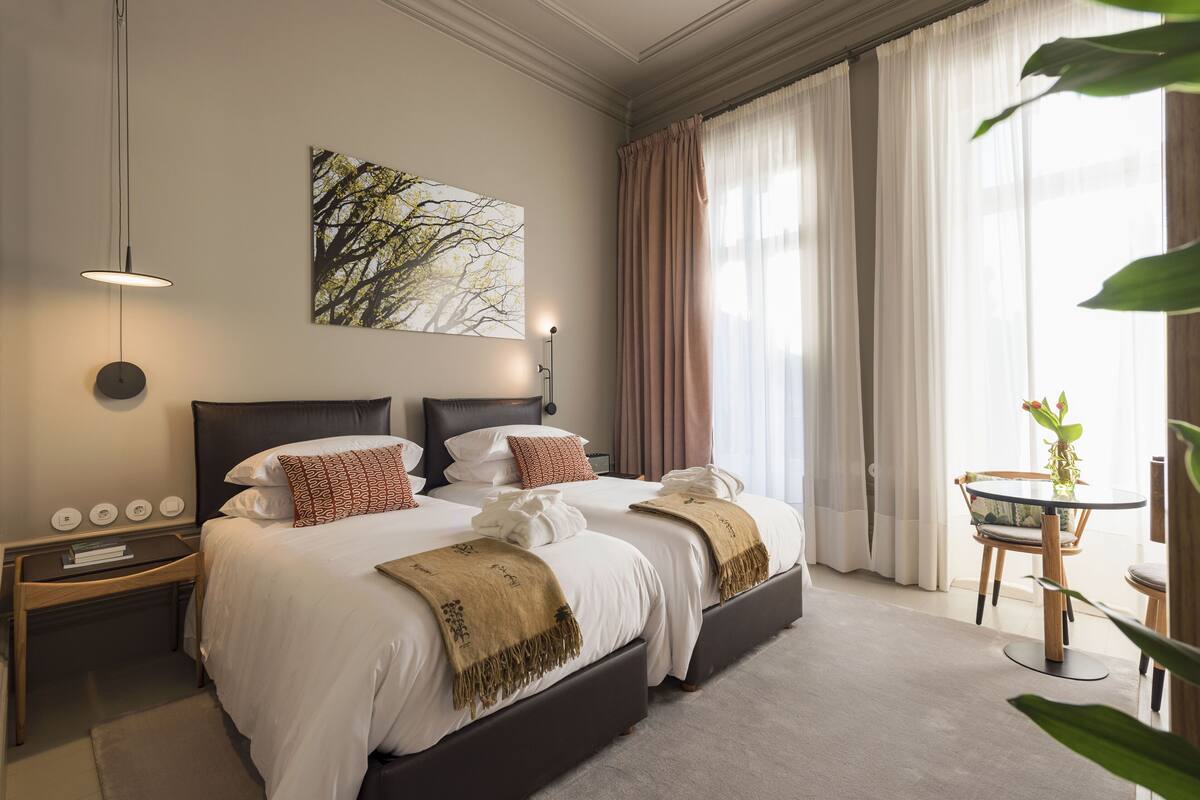 A hotel room with a large bed, bedside tables, a desk, and a chair.