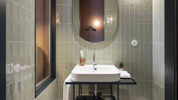 Un baño moderno con un espejo grande, un lavabo y un inodoro.