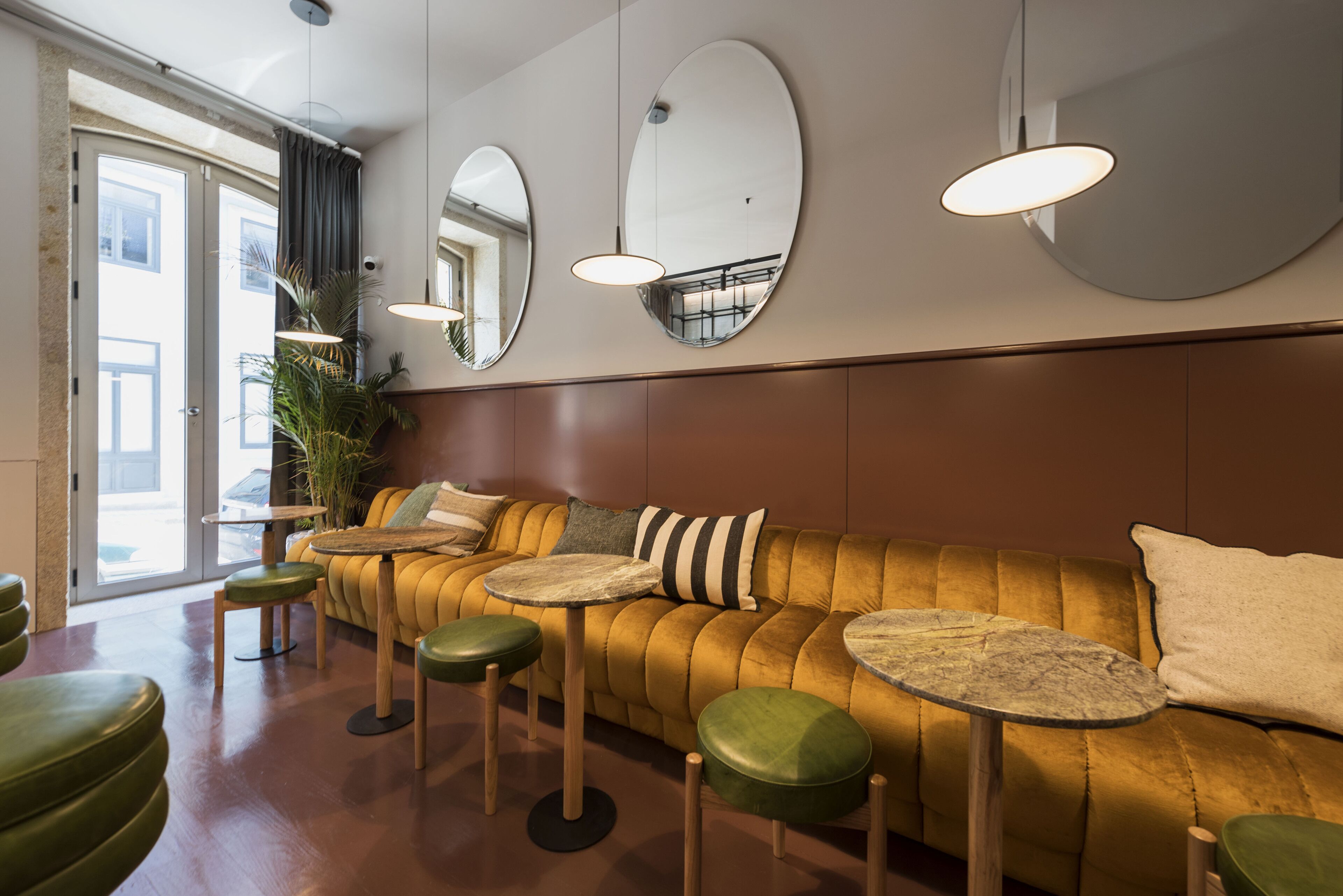 Un intérieur moderne avec un canapé jaune, des tables rondes et des tabourets verts.