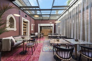Un restaurant doté d’un plafond en verre, de tables, de chaises et d’un coin salon confortable.