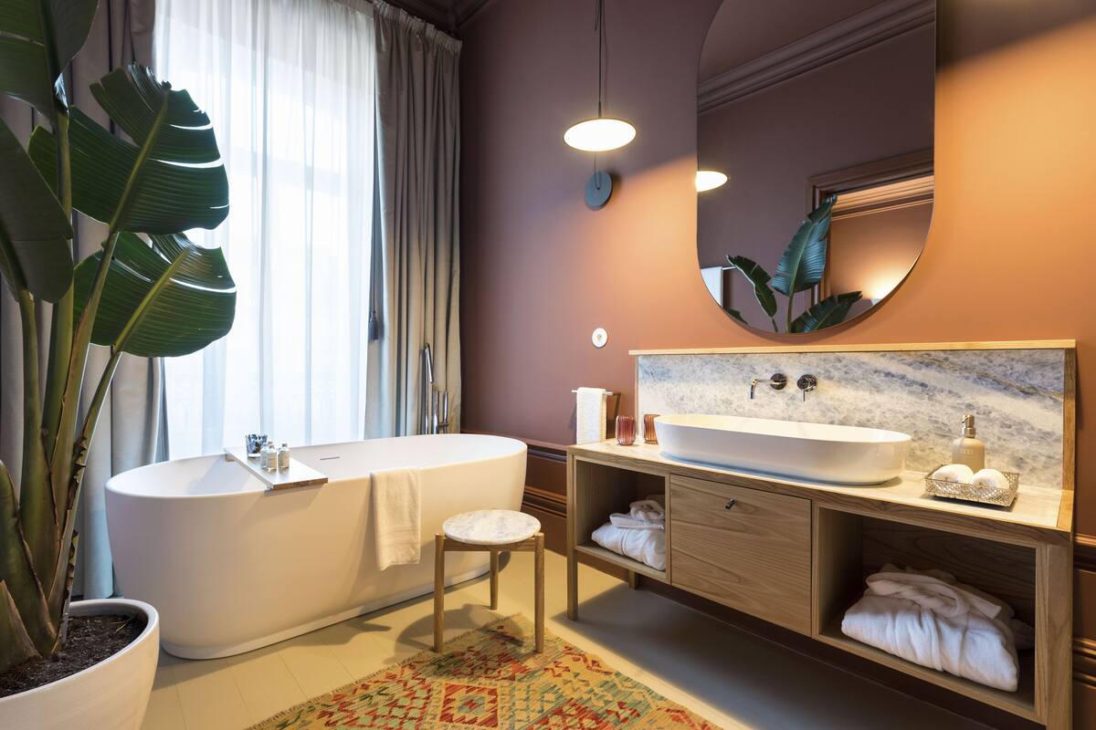 A modern bathroom with a freestanding bathtub, a large mirror, and a wooden vanity.