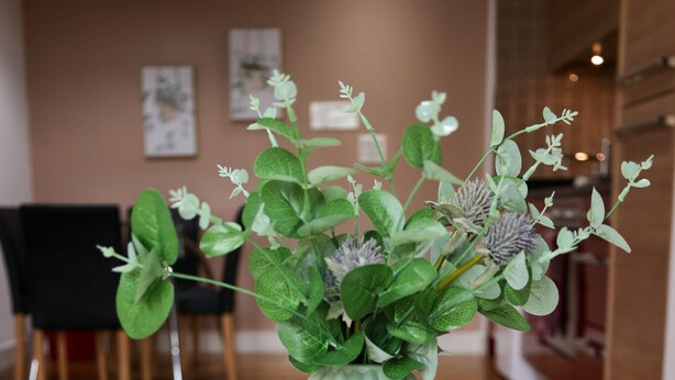 A green vase with a textured design on a white table.
