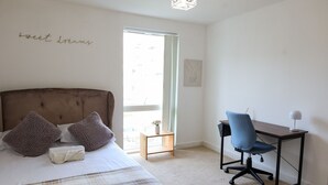 A bedroom with a bed, a desk, and a chair.