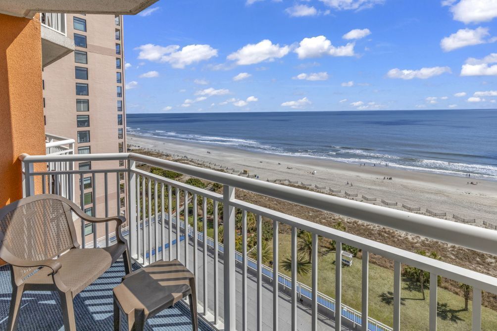 A balcony with a view of a beach and ocean.