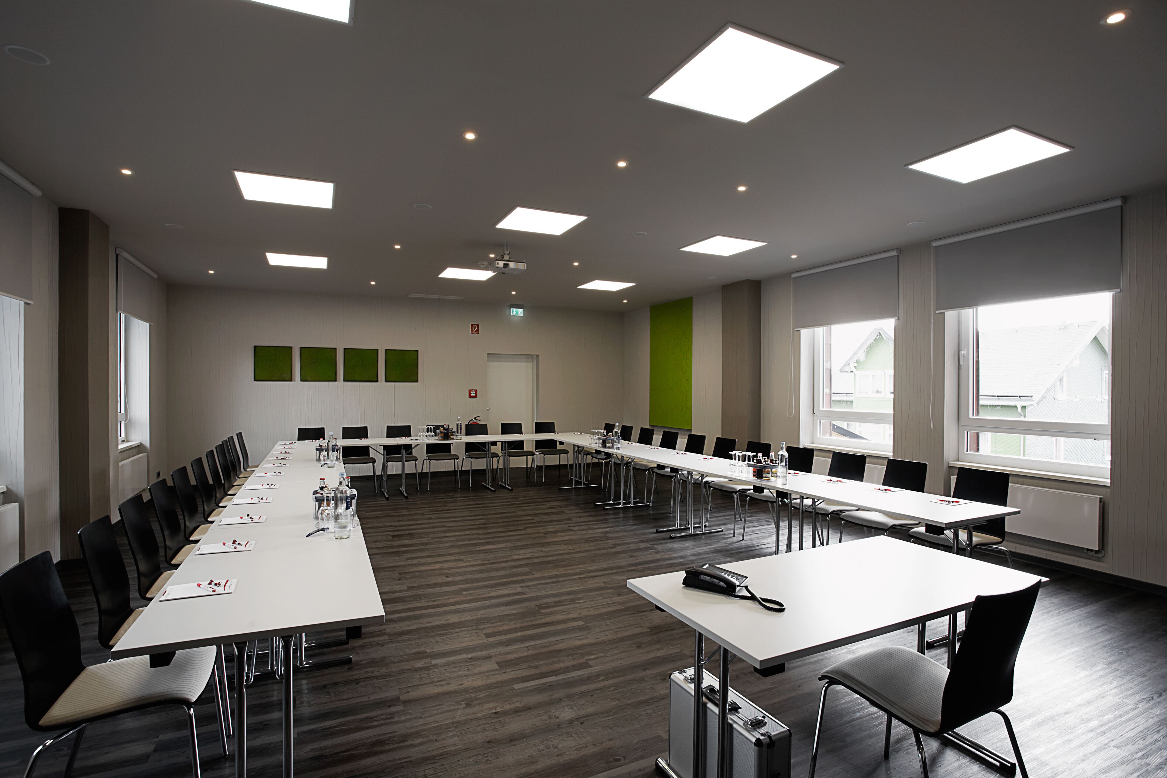 Ein Konferenzraum mit einem langen Tisch, Stühlen und einer Projektionsleinwand.