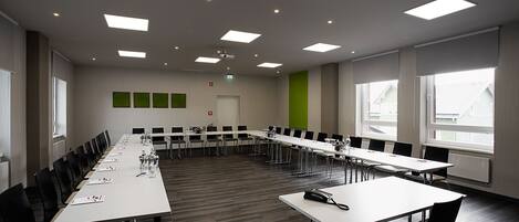 A conference room with a long table, chairs, and a projector screen.