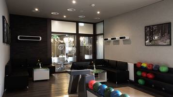 A bowling alley with a modern design, including a seating area with black sofas and a display of colorful bowling balls.