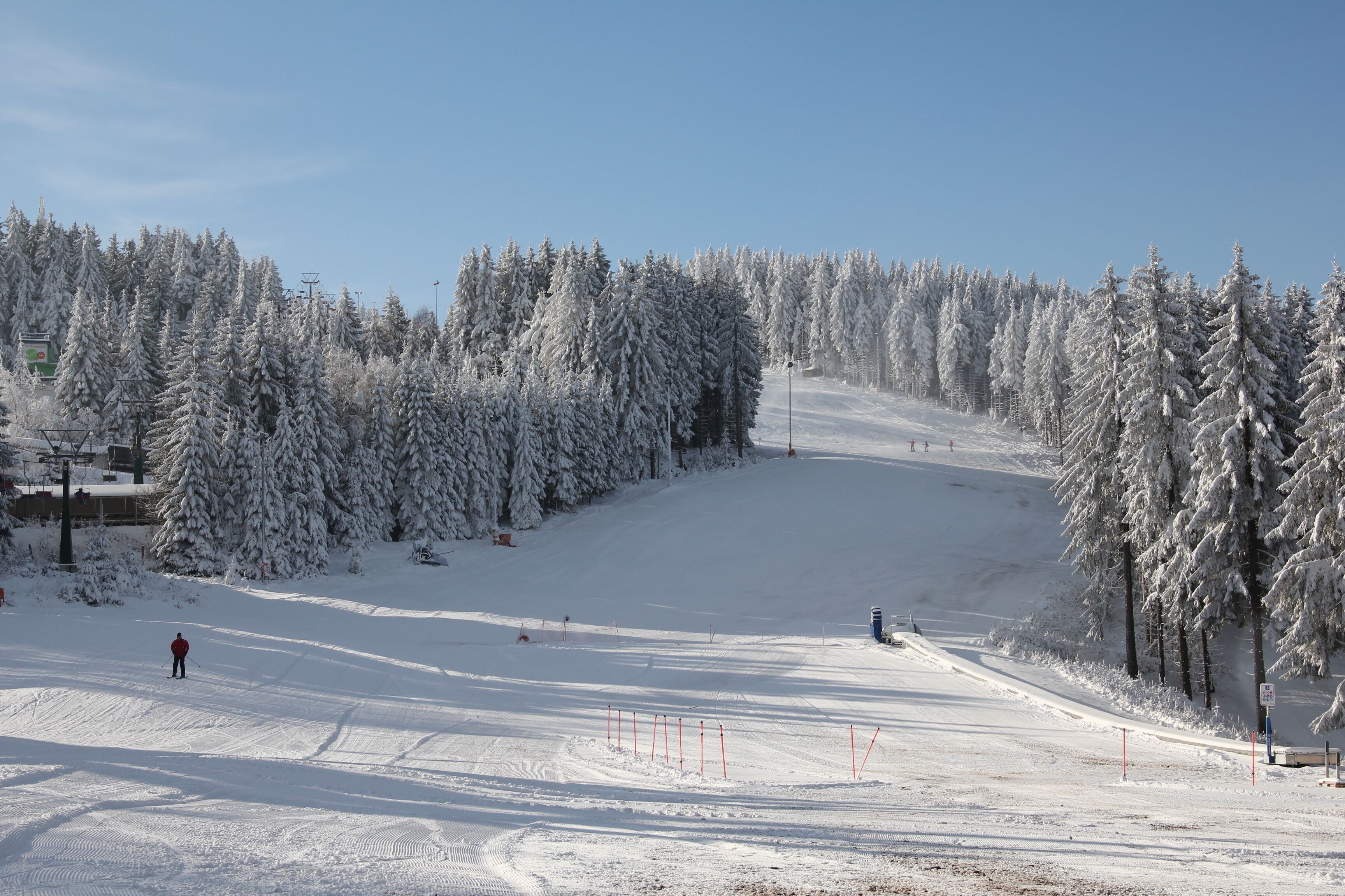 Pista d'esquí coberta de neu, amb arbres i un cel serè.