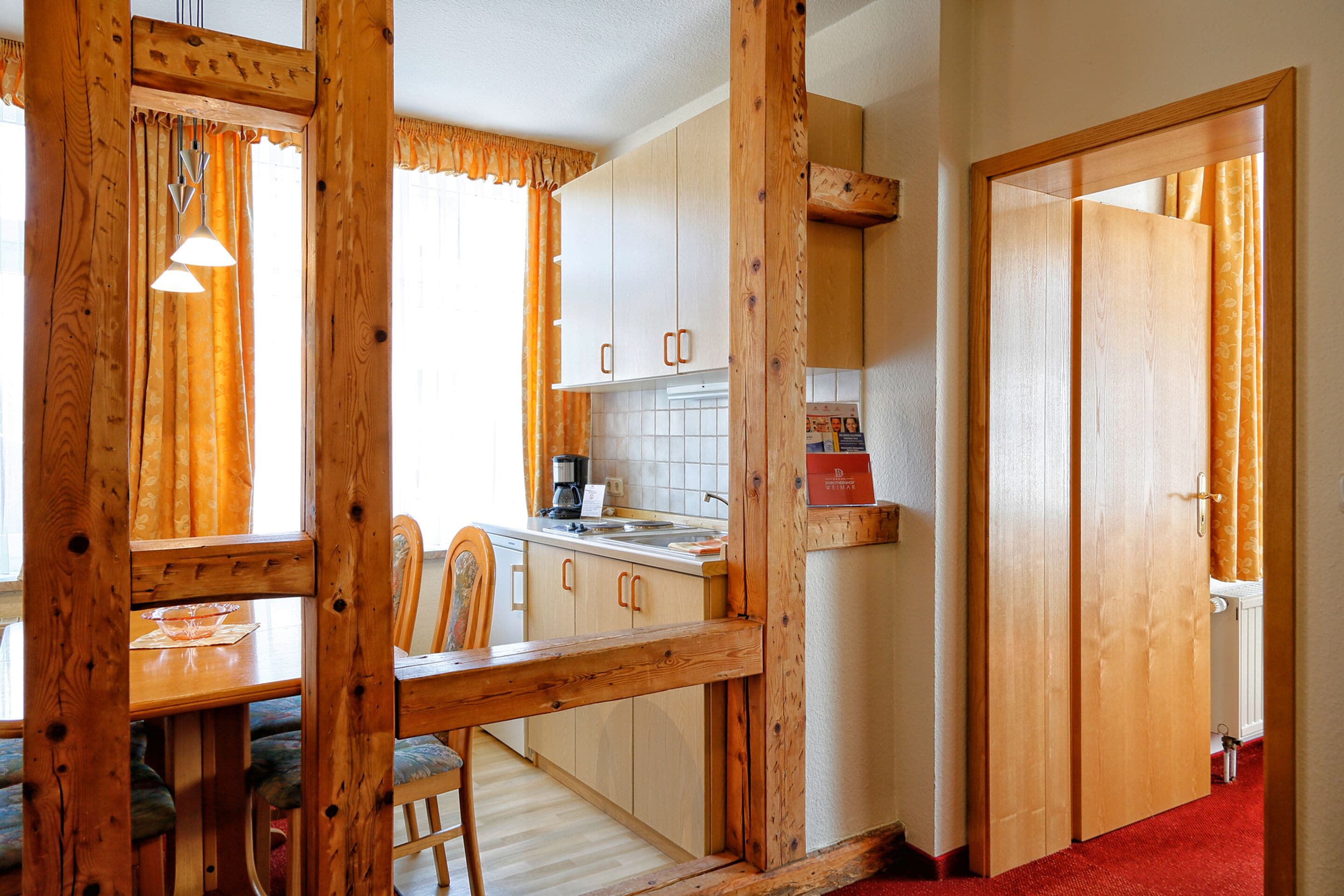 A wooden interior with a dining table, chairs, and a kitchen area with cabinets and a countertop.