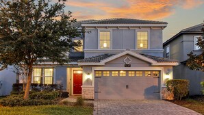 Una casa a due piani con una porta rossa, un garage e un giardino anteriore curato.