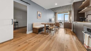 A modern apartment with a dining area, kitchenette, and a large window offering a view. - Laredo - Rooftop pool & Rainey St views (Austin)