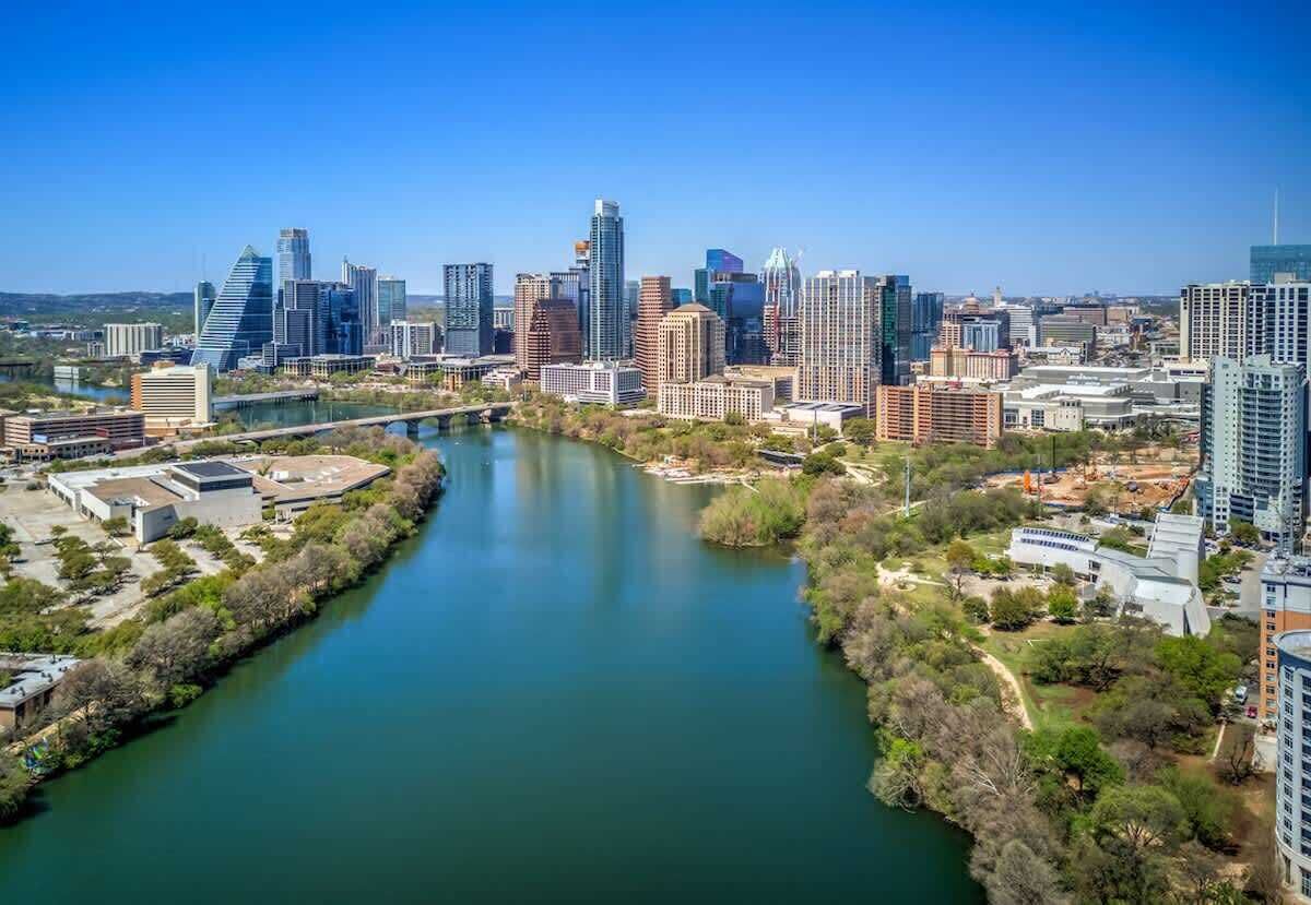 A cityscape with a river, modern buildings, and a bridge.