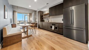 A modern kitchen with a built-in oven, a stainless steel refrigerator, and a dining area with a round table and chairs. - Laredo - Rooftop pool & Rainey St views (Austin)