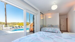 A bedroom with a large bed, a view of a swimming pool, and a door leading to a balcony. - Lovely vacation home with amazing views and private pool | Townhouse Calahonda (Mijas Costa)