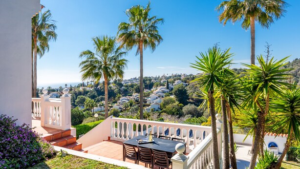 A terrace with a table and chairs, surrounded by palm trees and a view of a residential area. - Lovely vacation home with amazing views and private pool | Townhouse Calahonda (Mijas Costa)