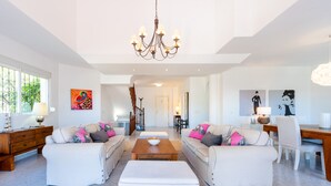 A spacious living room with two white sofas, a coffee table, and a chandelier. - Lovely vacation home with amazing views and private pool | Townhouse Calahonda (Mijas Costa)