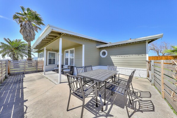 A patio area with a table and chairs, a covered seating area, and a wooden fence.