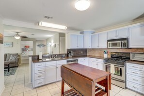 A modern kitchen with white cabinets, a built-in oven, a microwave, and a wooden island.
