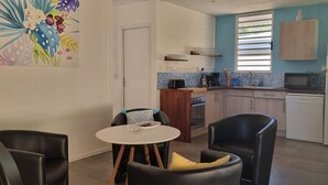 A compact kitchen with a dining area, featuring a microwave, refrigerator, and a small dining table with chairs. - In the heart of the village villa 6 people not 8 (Moorea)