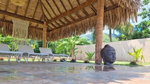 A covered outdoor area with lounge chairs and a Buddha statue. - In the heart of the village villa 6 people not 8 (Moorea)
