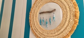 A woven wall hanging with a wooden stick and blue tassels.
