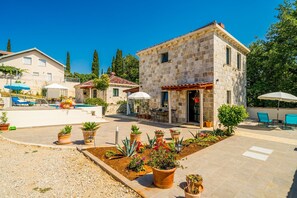 Un edificio de piedra con un patio, mobiliario exterior y una piscina.