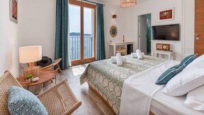 A hotel room with a bed, a desk, a TV, a balcony, and a view of the sea. - Mamma mia luxury rooms - Double Room with Sea View (Trogir)
