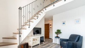 A modern living room with a staircase, a flat-screen TV, a potted plant, and a blue armchair. - Mamma mia luxury rooms - Duplex Double Room with Sea View (Trogir)