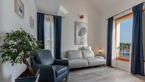 A living room with a sofa, a chair, a plant, and a painting on the wall. - Mamma mia luxury rooms - Duplex Double Room with Sea View (Trogir)