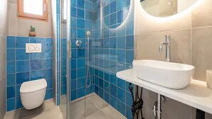 Une salle de bain moderne avec une douche à parois de verre, un lavabo blanc et des toilettes.