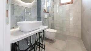 Ein modernes Badezimmer mit einem großen weißen Waschbecken, einer Duschkabine aus Glas und einer Toilette.