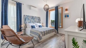 Ein modernes Schlafzimmer mit einem großen Bett, einem Sessel, einem Schreibtisch und einem Spiegel.