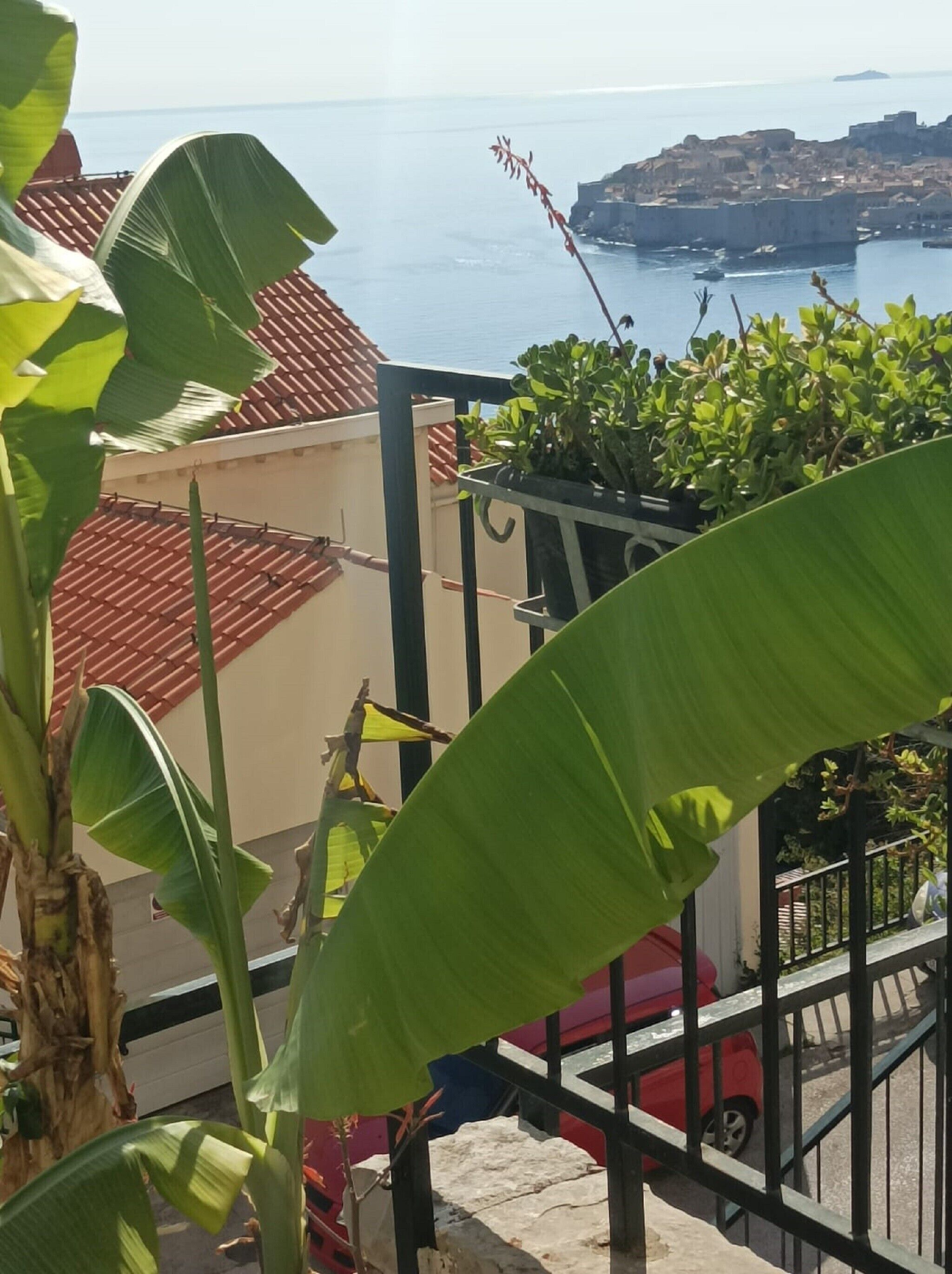 A balcony with a view of the sea and a distant town.