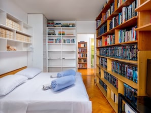 Une chambre d’hôtel avec un lit, une grande bibliothèque et une salle de bain visible à travers une porte ouverte.