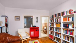 Un salon avec un canapé en cuir marron, un meuble rouge et une bibliothèque remplie de livres.