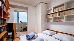 Une chambre à coucher avec un lit, une bibliothèque, un tapis de course et une vue par la fenêtre.