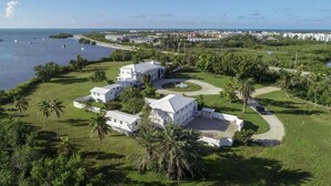 Una propiedad costera con varias construcciones blancas, un césped cuidado y vista al océano.
