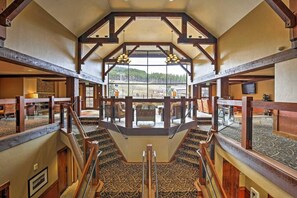 A hotel lobby with a central staircase, wooden beams, and large windows offering a view of the outdoors. - Modern Breckenridge Penthouse.  Ski-in/ski-out! (Breckenridge)